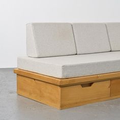 a couch that is sitting on top of a wooden box with two drawers underneath it