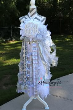 a mannequin is adorned with white feathers and monogrammed letters