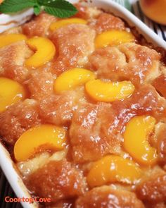 a close up of a cake in a pan with peaches on top and leaves