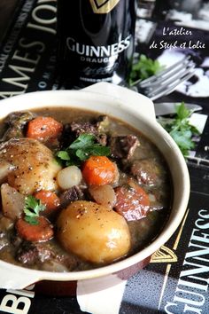 a white bowl filled with stew and carrots on top of a black table cloth