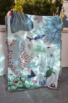 a blanket with sea animals and corals on it sitting on top of a sidewalk