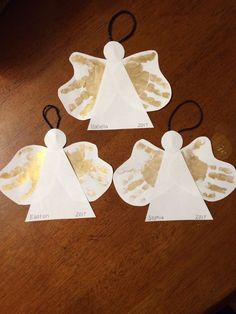 three angel ornaments made out of paper on a table