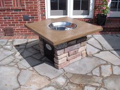 a fire pit sitting on top of a stone patio next to a brick wall and door