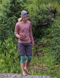 a woman is walking down the road with an apple in her hand and wearing a hat