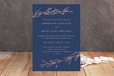 a blue and gold wedding card on a wooden table