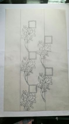 a piece of paper that has been drawn with flowers and vines on it, sitting on top of a table