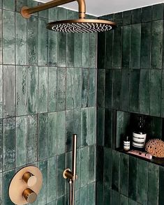 a green tiled shower with gold faucet and soap dispenser next to it