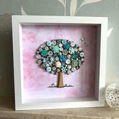 a button tree in a white frame on a mantle