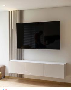 a flat screen tv mounted to the side of a white wall in a living room