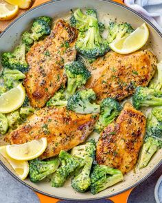 chicken and broccoli in a skillet with lemon wedges on the side