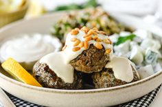 a bowl filled with meatballs covered in white sauce