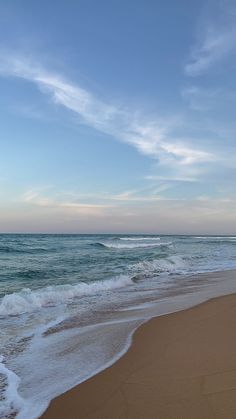 the ocean waves are rolling in and out on the shore line, with blue skies above