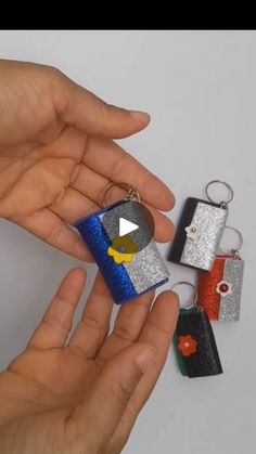 a person is holding four different keychains in their hands