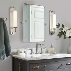 a bathroom with a sink, mirror and flowers on the counter in front of it