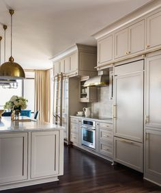 a large kitchen with white cabinets and wood flooring, along with an island in the middle