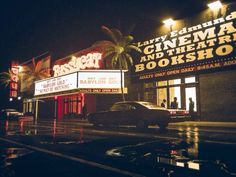 a movie theater at night with cars parked in front