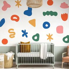 a baby's room with colorful wall decals and a crib in the foreground