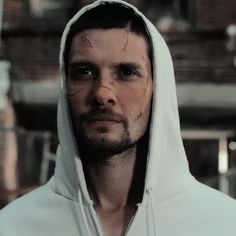 a man wearing a white hoodie looking at the camera