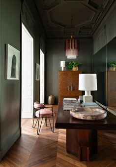 a living room filled with furniture next to a tall wooden table and two lamps on top of it