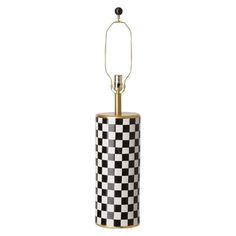 a black and white checkerboard lamp with a gold metal holder on the side