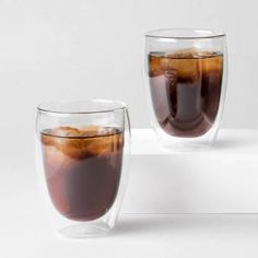 two glasses filled with liquid sitting on top of a white counter next to each other