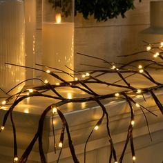 some candles are sitting on a window sill decorated with branches and lite - up lights