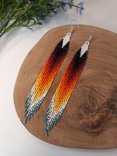 two pairs of beaded earrings on top of a wooden board