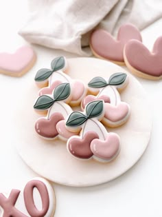 cookies decorated with pink and green leaves are on a white plate next to the word xo