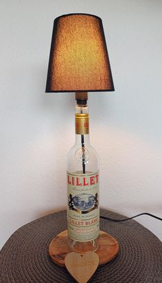 a bottle lamp sitting on top of a table next to a wooden base with a brown shade