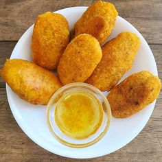 some fried food on a white plate next to a small bowl of mustard and ketchup