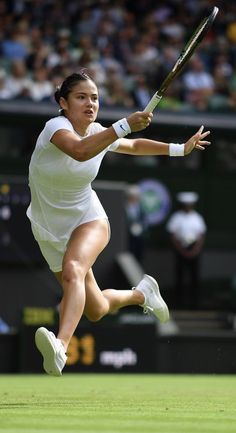 a female tennis player is running and swinging her racket at the ball during a match