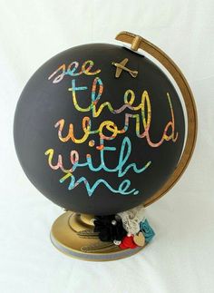 a black globe with writing on it next to a bottle of paint and a brush