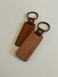 two wooden keychains sitting next to each other on top of a white table