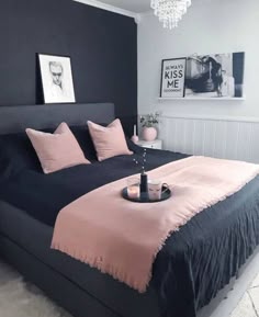 a black and pink bedroom with chandelier above the bed, pictures on the wall