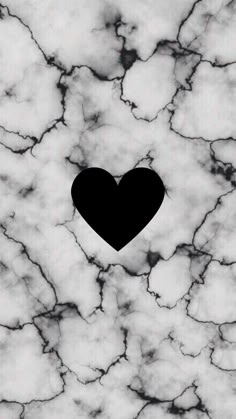 a black heart sitting on top of a white marble wall with the shape of a heart