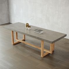 a coffee table with a book on it and a candle next to it in front of a white wall