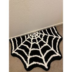 a black and white spider web rug is on the floor in front of a wall