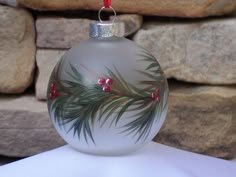 a glass ornament with red berries and green leaves on it sitting on a table