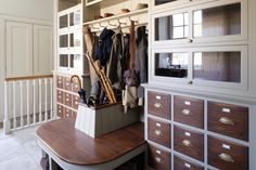 an organized closet with clothes hanging on the wall and wooden drawers in front of it