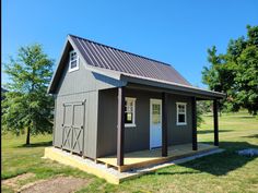 a small gray shed with a white door and windows on the front porch is shown