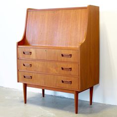 an old wooden desk with drawers on it's sides, against a white wall