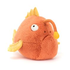 an orange stuffed animal with yellow horns on it's head and eyes, sitting in front of a white background