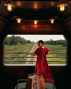 a woman in a red dress standing on a train