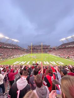 a football stadium filled with people watching a game on a cloudy day at dusk or dawn