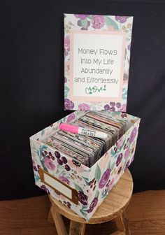 a wooden stool with a bunch of books in it and a sign that says money flows into my life abundantly and effortlessly