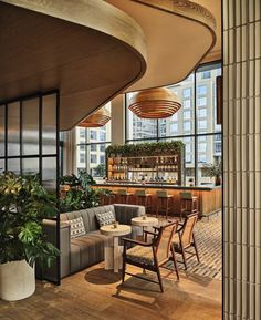 the interior of a restaurant with wooden tables and chairs, potted plants, and large windows