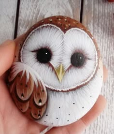 a hand holding an owl ornament on top of a wooden table