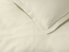 an unmade bed with white sheets and pillows on top of it, close up