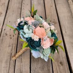 a bridal bouquet on a wooden table with succulents and flowers in it