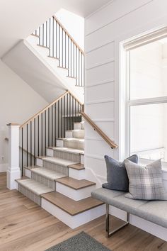 a set of stairs leading up to the second floor in a home with white walls and wood floors